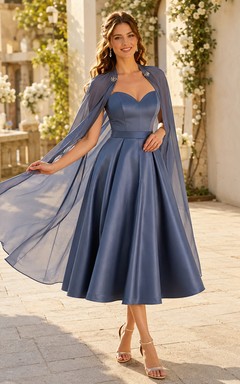 Vestido de invitada midi completo de satén azul acero con escote corazón y capa desmontable.