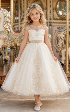 Vestido de niña de las flores color marfil con mangas cortas transparentes, corpiño con escote corazón, falda de tul en línea A hasta la rodilla y lazo bordado dorado en la cintura.