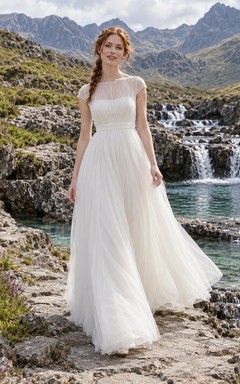 Sencillo vestido de novia de tul con corte en A, escote ilusión tipo barco y mangas cortas transparentes.