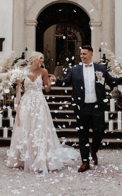 Robe de mariée de plage en tulle, coupe trapèze, ornée de dentelle et d'appliqués, avec un décolleté en V plongeant et une traîne courte. Décolleté plongeant dans le dos et fines bretelles spaghetti. Traîne courte.