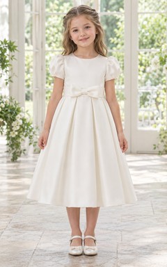 Schlichtes, dezentes elfenbeinfarbenes, teelanges Blumenmädchenkleid aus weichem, plissiertem Satin mit Puffärmeln, schmaler Schleife.