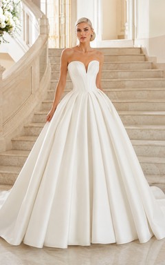 Robe de bal bustier en satin harmonieux, décolleté cœur, traîne cathédrale et plis, idéale pour un mariage à destination.