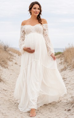 Vestido de novia bohemio de maternidad con hombros descubiertos, mangas largas de encaje ilusión y falda escalonada de gasa.