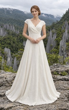 Schlichtes, bodenlanges A-Linien-Brautkleid mit V-Ausschnitt, kurzen Ärmeln und Wickeloptik – perfekt für eine Gartenhochzeit.