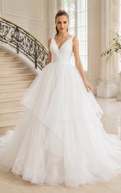 Robe de mariée romantique de style chapelle, ornée de bretelles en V et de volants en tulle à plusieurs niveaux.