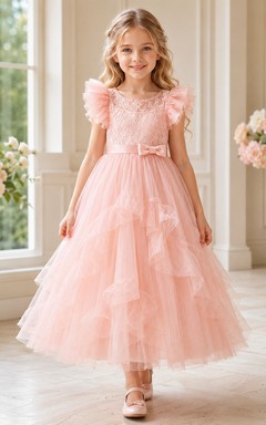 Robe de demoiselle d'honneur rose pêche en tulle superposé, coupe trapèze, avec volants, manches pétales et nœud.