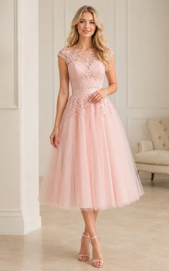Vestido de invitada de corte A, largo midi, con escote barco, manga corta, tul, encaje, pedrería, efecto ilusión y cremallera en la espalda.