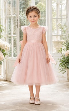 Robe de demoiselle d'honneur en tulle rose poudré à manches à volants, coupe trapèze, avec nœud, en dentelle et longueur thé. Idéale pour un mariage champêtre.