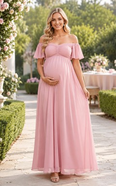 Robe de maternité rose poudré en mousseline rose poudré, épaules dénudées, manches papillon, style empire, longueur au sol, idéale pour une garden-party.