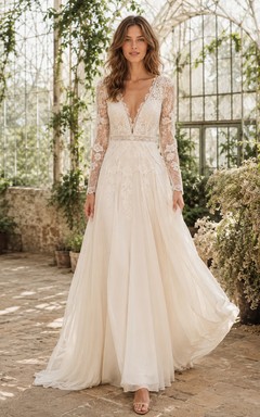 Robe de mariée classique en mousseline et dentelle, décolleté plongeant en V, manches longues, coupe trapèze, traîne, dos nu plongeant, manches longues et bustier trapèze.