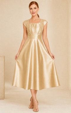 Vestido de noche de corte A, largo hasta la rodilla, sin mangas, con escote cuadrado y acabado en satén dorado intenso.