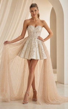 Vestido corto de quinceañera color champán, sin tirantes, con escote corazón, encaje, brillos y sobrefalda desmontable.