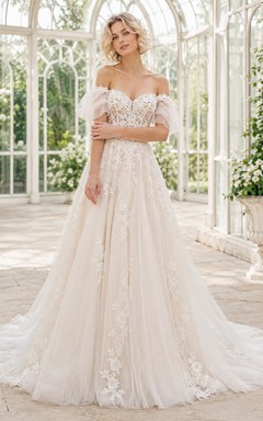 Robe de mariée élégante en dentelle et tulle, épaules dénudées, manches courtes, coupe trapèze, traîne chapelle, ornée d'appliqués floraux, au bord d'un lac