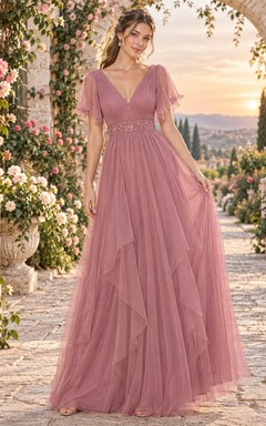 Vestido largo de invitada color rosa empolvado con escote en V, mangas con volantes y caída en cascada.