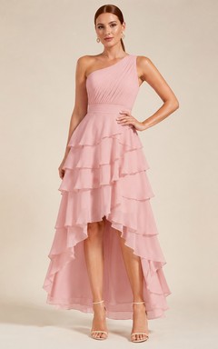 Robe trapèze en tulle rose poudré à une épaule, à volants et ourlet asymétrique.