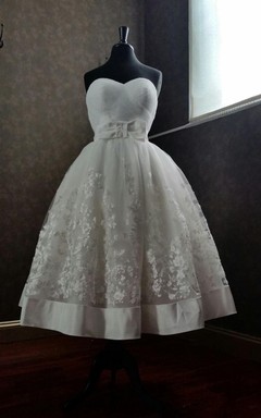 Robe de première communion en organza et dentelle, coupe trapèze, longueur thé, décolleté cœur, avec nœud.