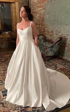Vestido de novia sencillo de satén con tirantes finos, corte imperio y silueta acampanada.