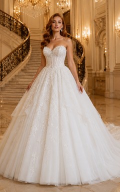 Vestido de novia de tul, estilo princesa, sin tirantes, con cola larga, detalle de volantes y escote en V en la espalda.