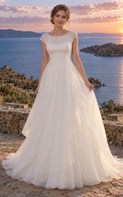 Vestido de novia de organza con escote ilusión, mangas cortas y corte en A, con superposición drapeada.