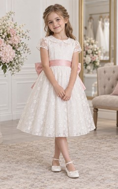 Vestido de niña de flores vintage blanco con estampado floral, corte en A, mangas cortas de encaje y fajín rosa, largo hasta la rodilla.