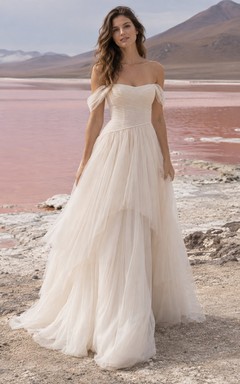 Vestido de novia de tul con escote Bardot, corte en A, corpiño fruncido y falda asimétrica de capas.