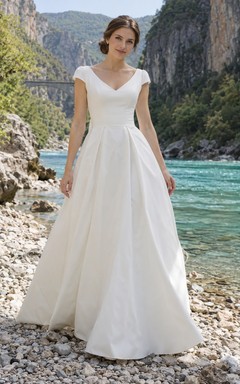 Vestido de novia sencillo de corte A con escote en V, mangas cortas y espalda ladeada con pliegues.
