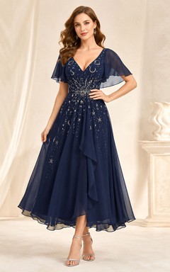 Vestido de invitada azul marino oscuro con escote en V, de gasa con cuentas y corte asimétrico.