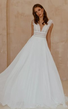 Robe de mariée bohème en mousseline de soie et dentelle, col en V, coupe trapèze, manches courtes, longueur au sol et traîne.