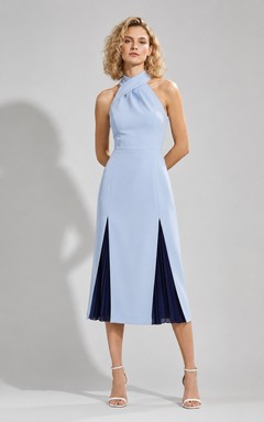 Vestido de cóctel azul cielo de punto, sin mangas, con cuello halter, corte recto, largo hasta la rodilla y abertura frontal.