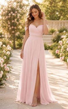 Robe longue fendue en mousseline rose poudré, épaules dénudées, manches courtes, coupe trapèze, longueur au sol.