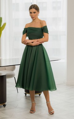 Vestido sencillo de gasa estilo imperio con hombros descubiertos y corte en A, largo hasta la rodilla.
