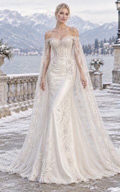 Vestido de novia romántico de invierno estilo sirena con capa transparente, bordado en plata y hombros descubiertos.