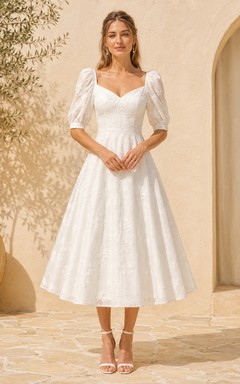 Robe de mariée mi-longue en dentelle, décolleté cœur, manches bouffantes, fermeture éclair au dos nu.