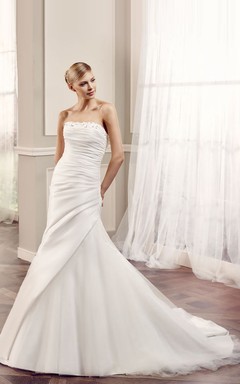 Robe de mariée sirène en satin, sans manches, bustier, dos nu et perles, avec drapé latéral sur les côtés.