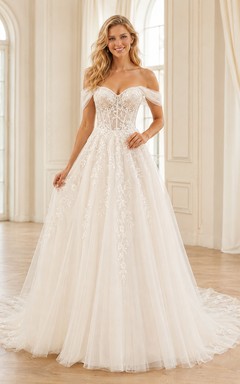 Robe de mariée champêtre en tulle et dentelle aérienne, épaules dénudées, manches courtes, coupe trapèze, traîne chapelle, ornée d'appliqués floraux.