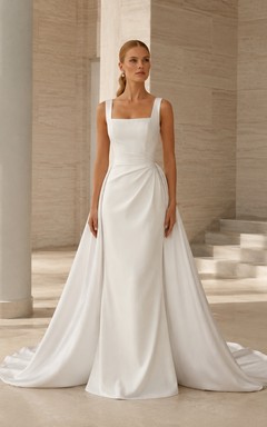 Robe de mariée style domaine, en satin transparent, bretelles carrées, sans manches, coupe trapèze, traîne courte et surjupe drapée.