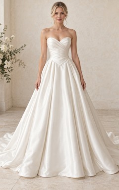 Vestido de novia sencillo sin tirantes, escote corazón, cintura vasca, satén drapeado y cola capilla.