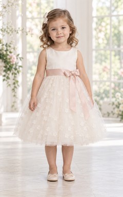 Robe de demoiselle d'honneur rose à fleurs, longueur thé, coupe trapèze, en tulle, sans manches, avec ceinture rose.