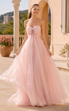 Robe de mariée en tulle rose poudré à fines bretelles, décolleté cœur et nœud oversize, coupe trapèze, bretelles spaghetti et bustier.