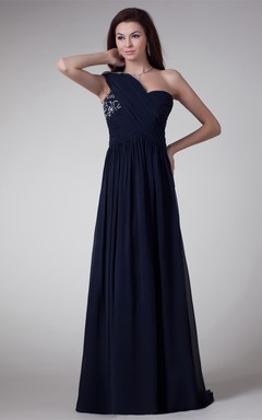 Robe longue asymétrique en mousseline de soie, coupe trapèze, ornée de cristaux et dévoilant une épaule.