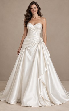 Vestido de novia sencillo, sin tirantes, con escote corazón asimétrico y cola larga de satén drapeada.