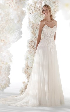 Robe de mariée vaporeuse et simple en tulle, dos nu, bretelles spaghetti, appliques de dentelle et fronces.