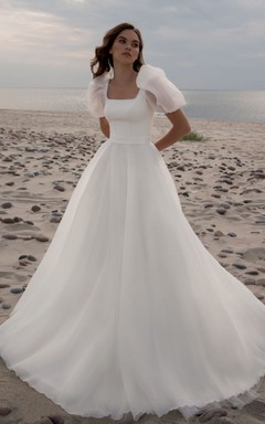 Robe de mariée simple en mousseline de soie, coupe trapèze, décolleté arrondi et traîne courte, ornée de fronces.