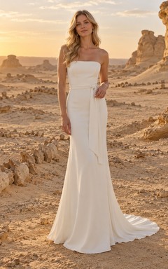 Vestido de novia sencillo, sin tirantes, de satén, con corpiño liso, cintura natural y cola larga hasta el suelo.