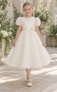 Schlichtes elfenbeinfarbenes, teelanges Organza-Blumenmädchenkleid mit abgerundeten Puffärmeln, geschwungener Schärpe und Rosettenapplikation