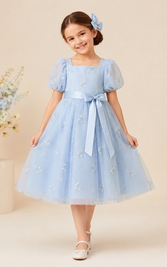 Sencillo vestido de niña de flores de tul con corte en A, cuello joya, falda a media pierna y falda plisada.