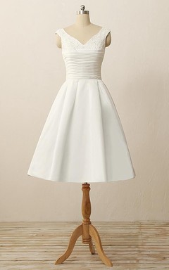 Robe courte en satin à col en V plissé et ornée de perles et d'appliques