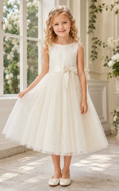Robe de demoiselle d'honneur élégante et romantique en tulle à pois suisses, col rond, sans manches, à double nœud, longueur thé, coupe trapèze, couleur champagne.