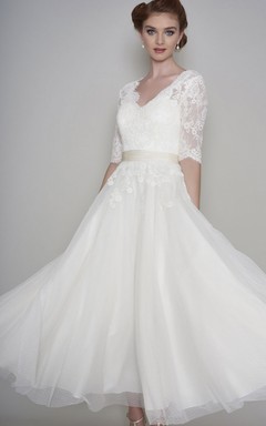 Robe de mariée courte en dentelle et organza, manches mi-longues, longueur cheville, ornée d'appliqués.