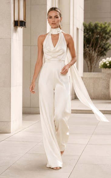 Mono de novia blanco con escote halter y drapeado, con fajín fluido.